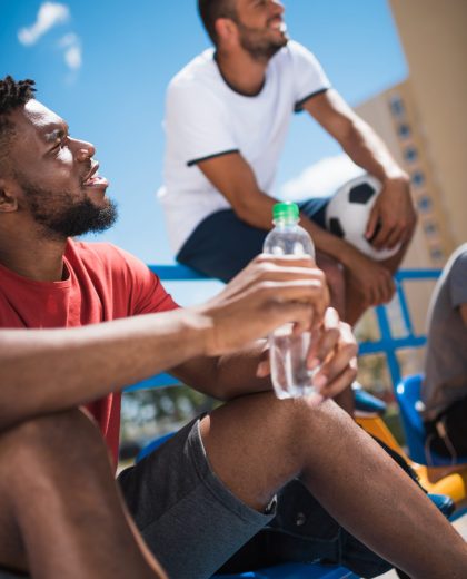 side view of african american man with water bottle resting on stadium